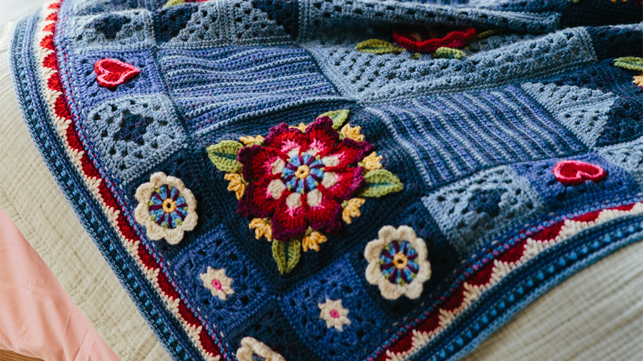 Intricate blue crochet blanket with 3D flower and heart motifs – ideal for your next crochet-along project.
