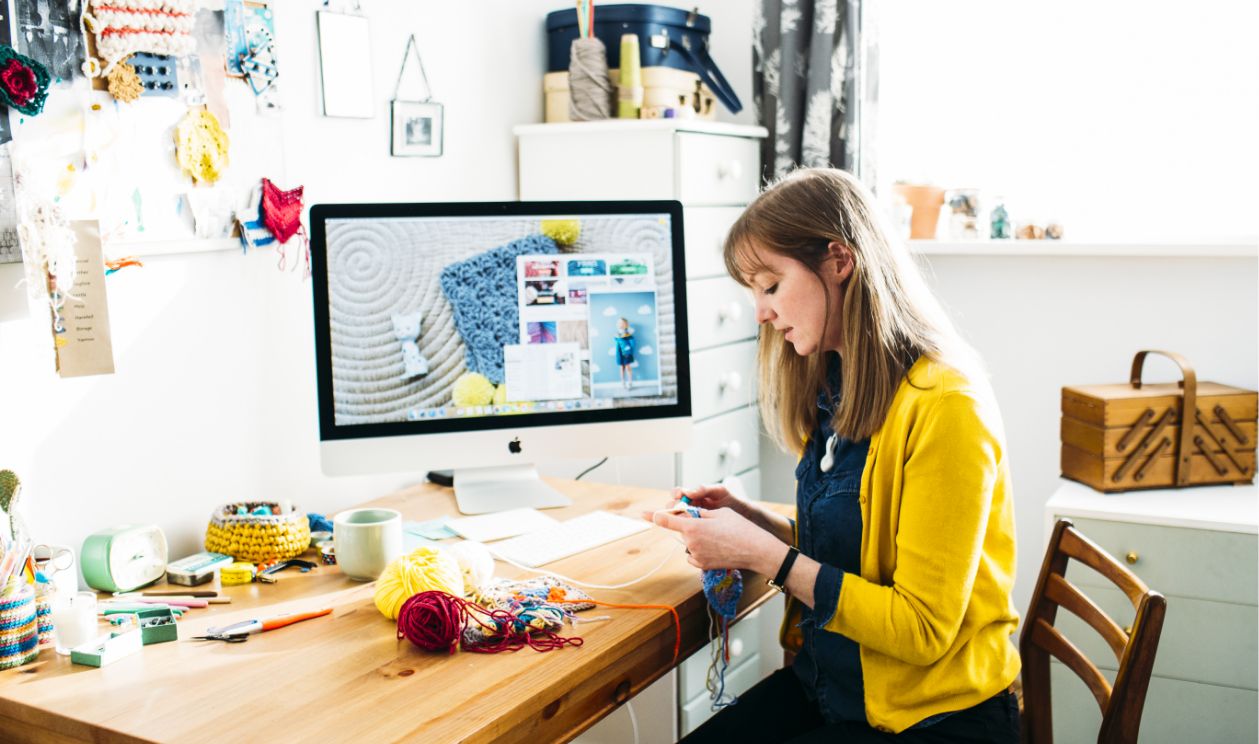 woman crocheting by her computer