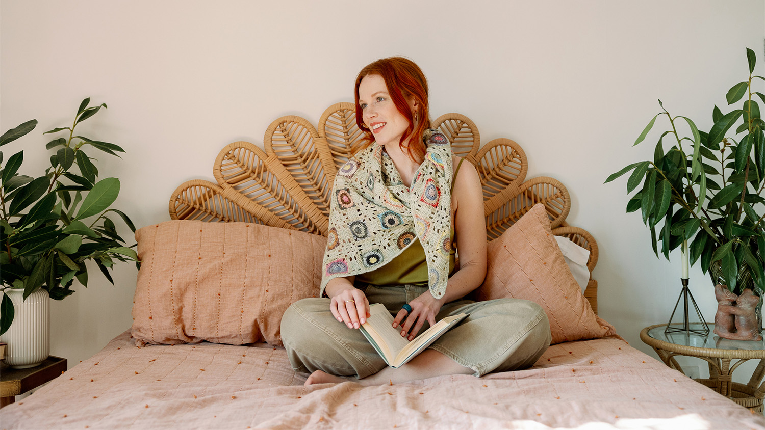 woman sitting on a bed reading a book