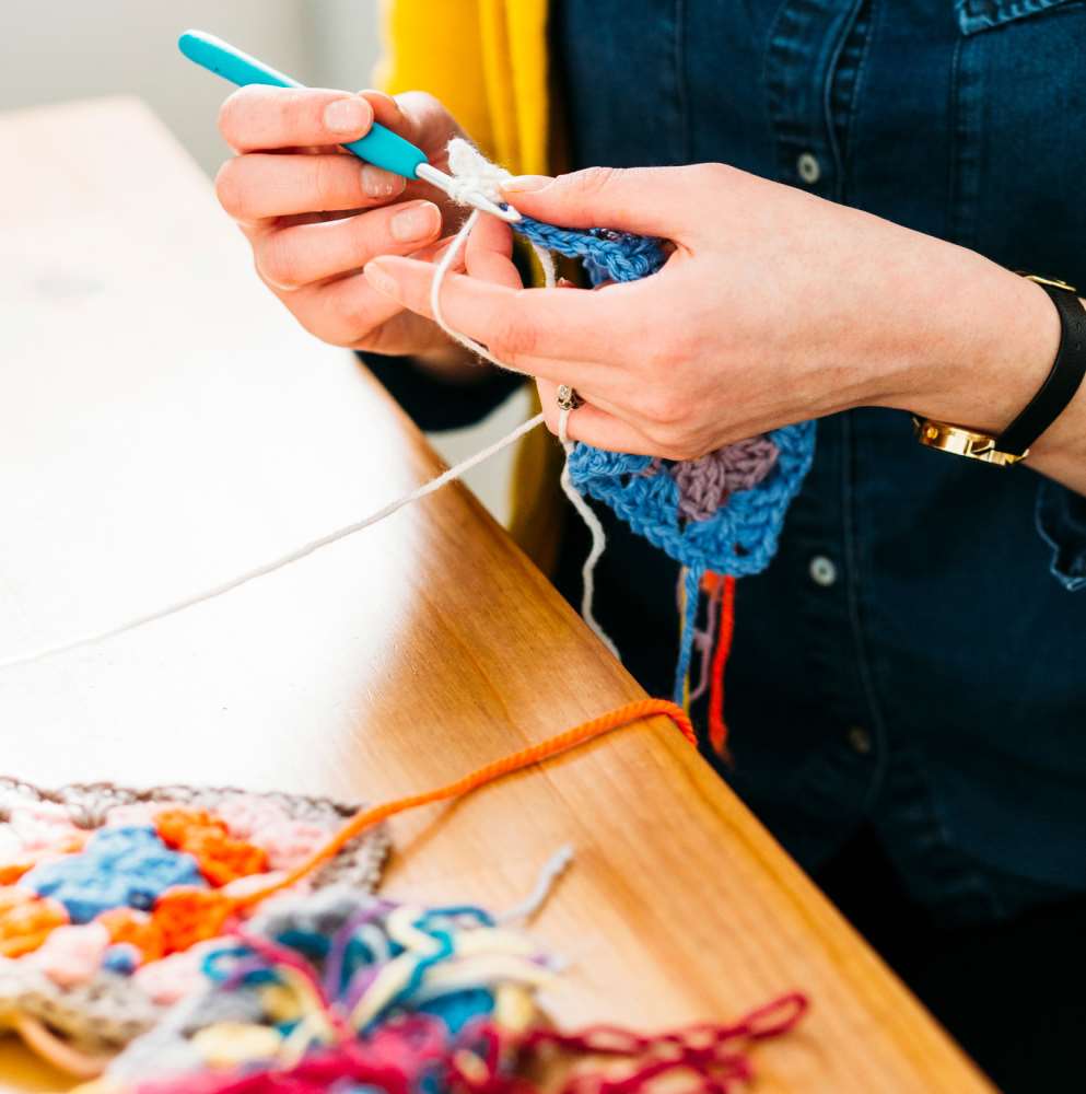 Learning how to crochet a granny square with a colourful yarn and hook